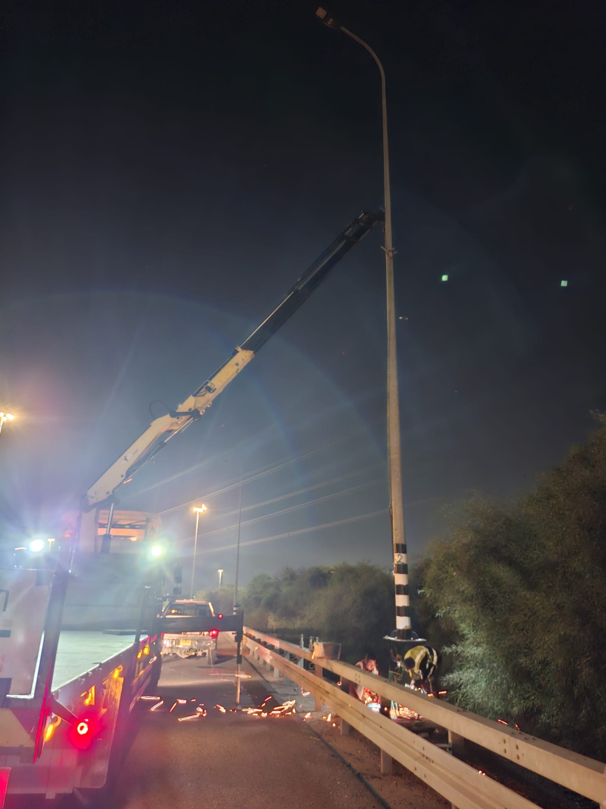 עבודת מנוף על עמוד תאורה בכביש בלילה
